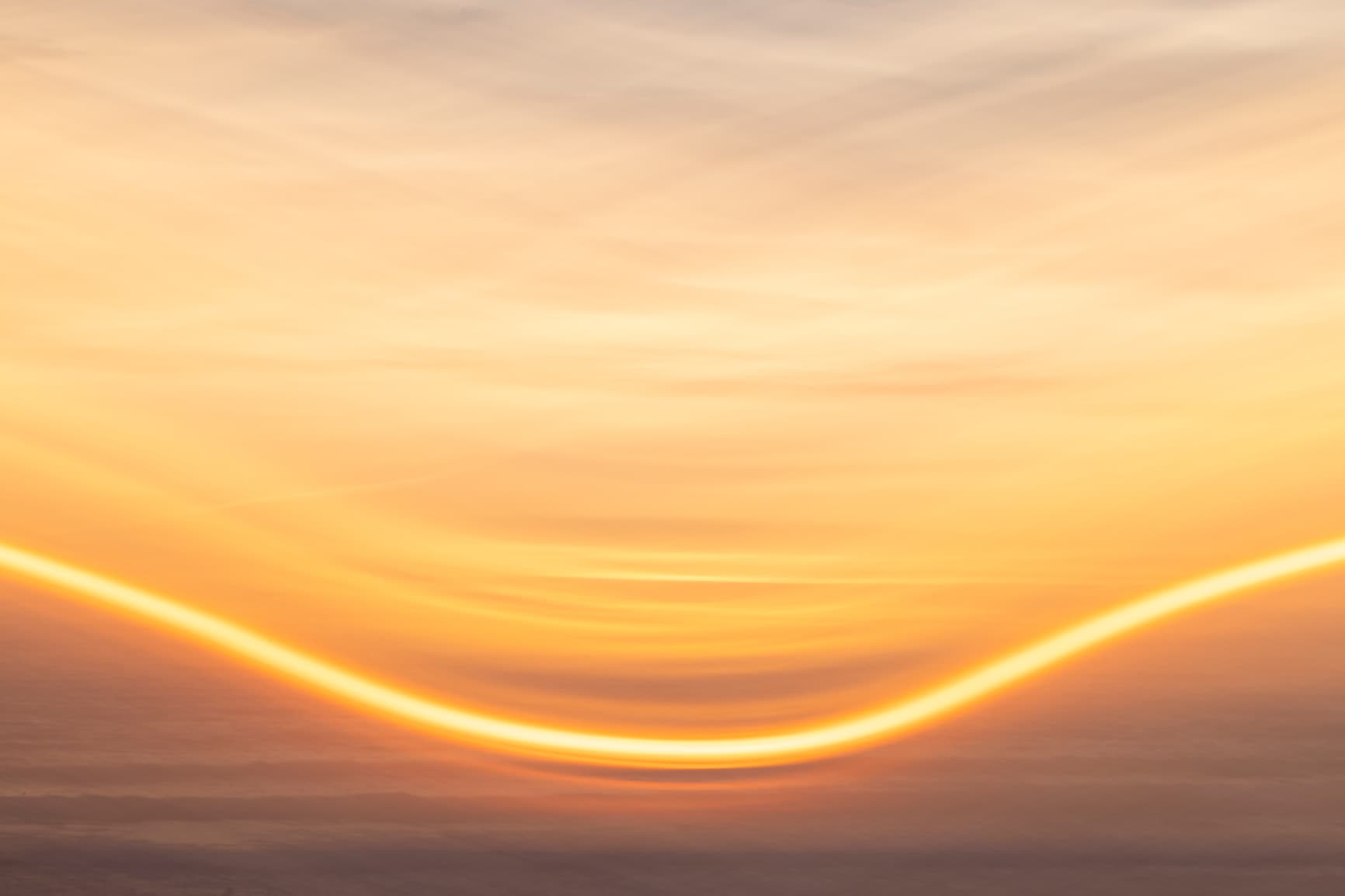 Golden light arc across a sunset horizon